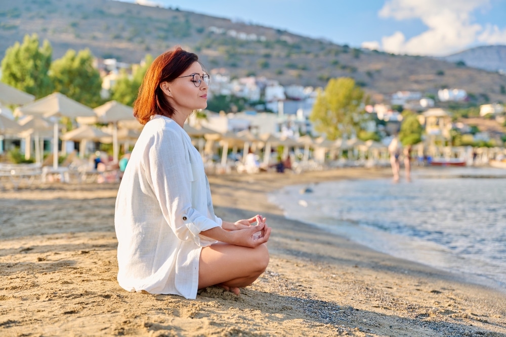LGBT woman sitting on a beach after she's learned about meditation for recovery