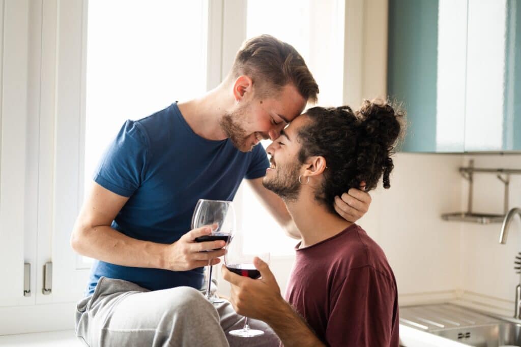 Two gay men drinking in their home and demonstrating how there might be a connection between alcoholism and the gay community
