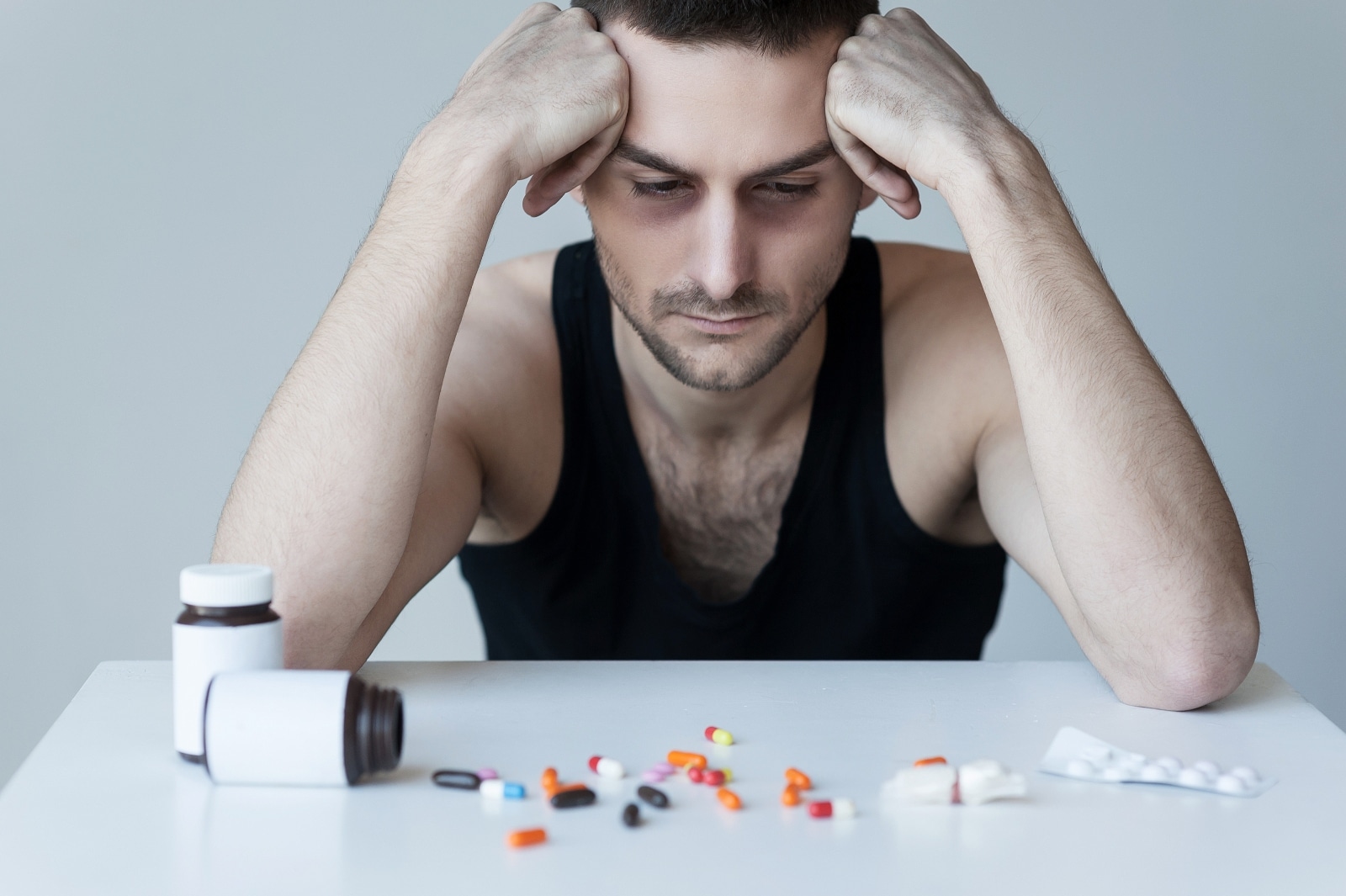 internalized homophobia and substance abuse - man sitting at table looking at pills