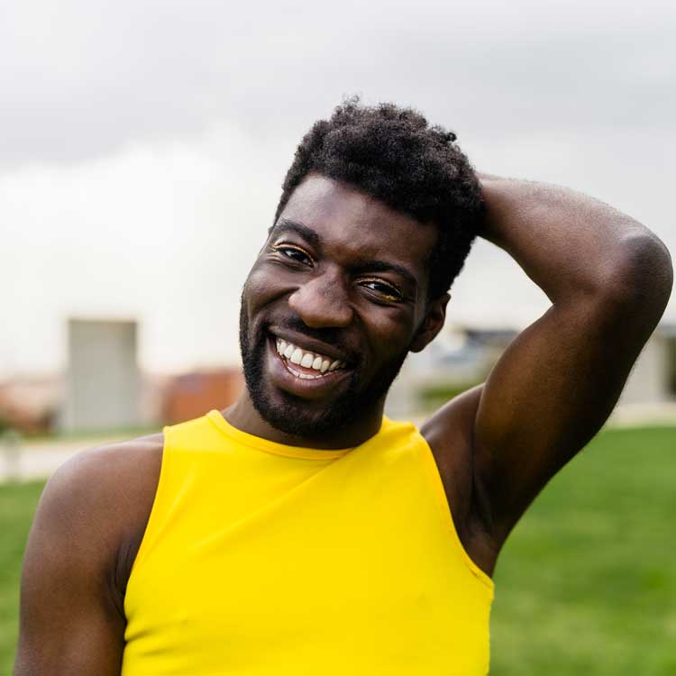 Happy black gay man with style and slight eye makeup.