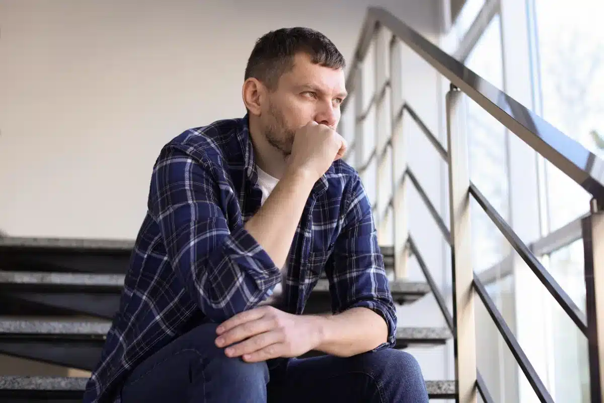 Thoughtful bisexual man sitting alone, reflecting on the unique addiction vulnerabilities and need for affirming care
