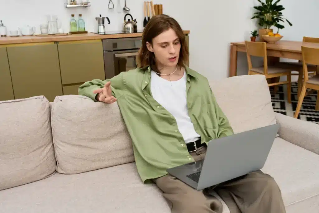 Queer adult attending a virtual IOP therapy session from home on a laptop in a private, comfortable space