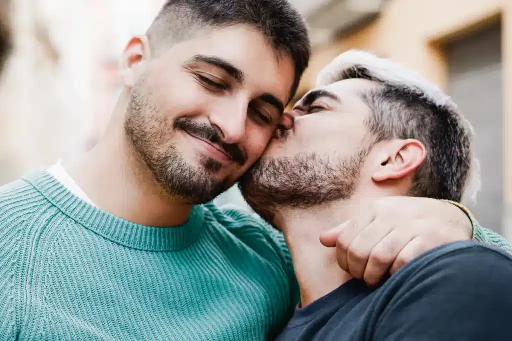 man kissing another man on the cheek in a quiet supportive moment during LGBTQ+ recovery from chemsex and meth